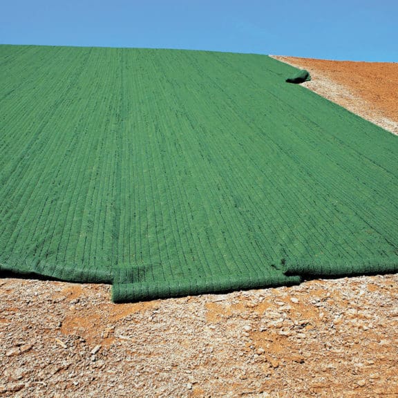 A large, blanket-like application of Turf Reinforcement Mats in an area with exposed, barren soil