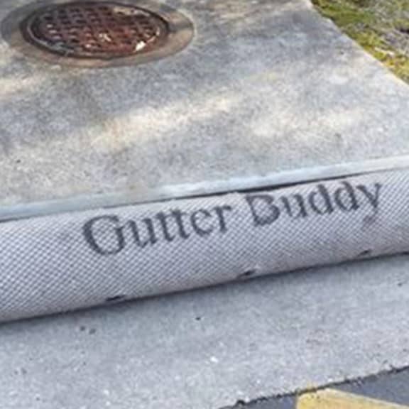 The high-flow inlet protection filter, GutterBuddy, laying in front of a roadside drain