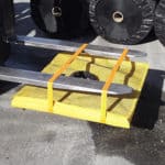 Construction workers using a pair of forks to lift a curb inlet filter