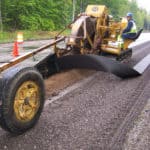 Construction workers installing strip drains to remove water from the surface of a road