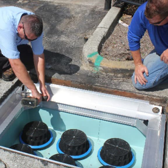 Two stormwater experts installing a new cartridge filter in a sub-surface chamber