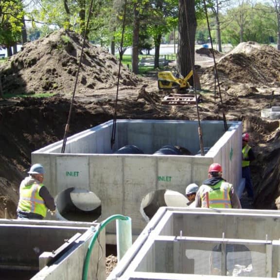 Experts lowering a stormwater vault with two Fabco Helix Filters into the ground