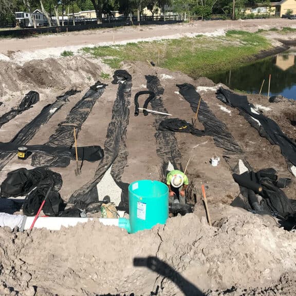 Stormwater management professionals laying drain tile on a construction site to direct stormwater