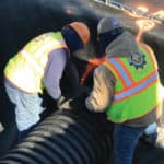 Two construction workers attaching a pipe to their R-Tank system