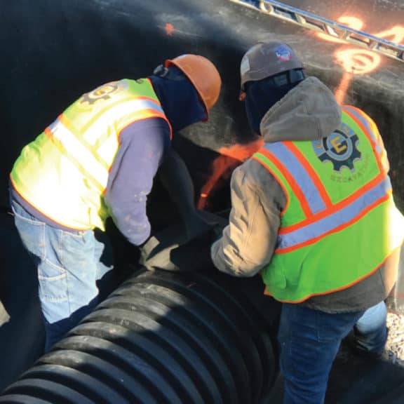 Two construction workers attaching a pipe to their R-Tank system