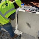 Construction worker moving large porous cement casts into position