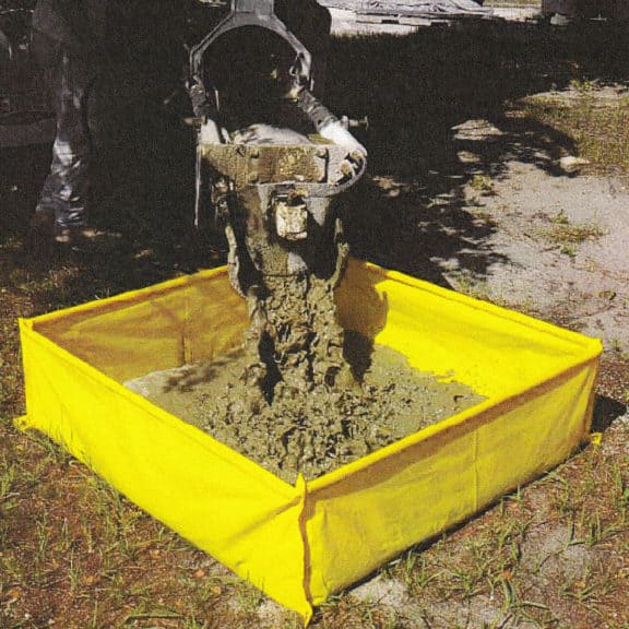 A cement truck pouring remnants into amaller washout berm