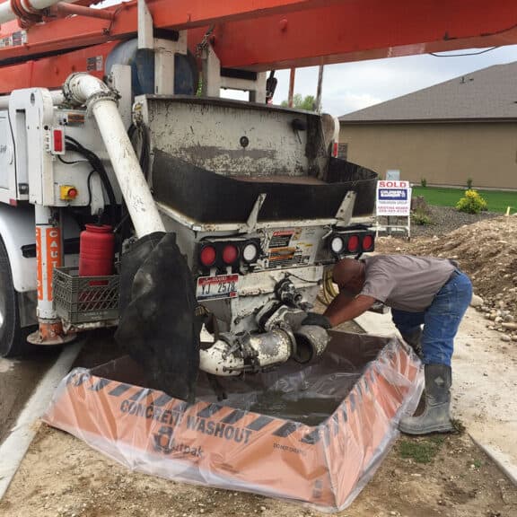 Large cement truck and construction worker over a washout berm