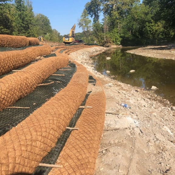 Coir Logs, also known as Bio Logs, set on an embankment next to a waterway