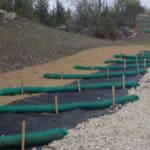 Multiple SiltSoxx lying across the ground, bridging sections of rock and sand