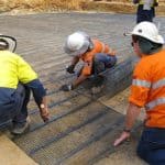 Construction workers installing high-strength ground geogrids