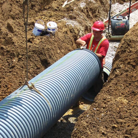 A professional installing HP Storm Pipe underground