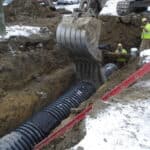 Stormwater drainage professionals installing N-12 on a construction site